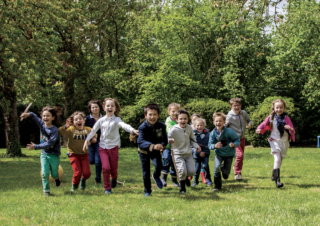 Les enfants courent et rient dans le jardin de La Chouette Bleue.
